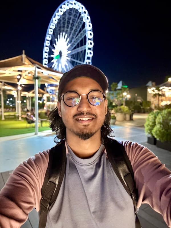A night-time selfie beside a lit ferris wheel