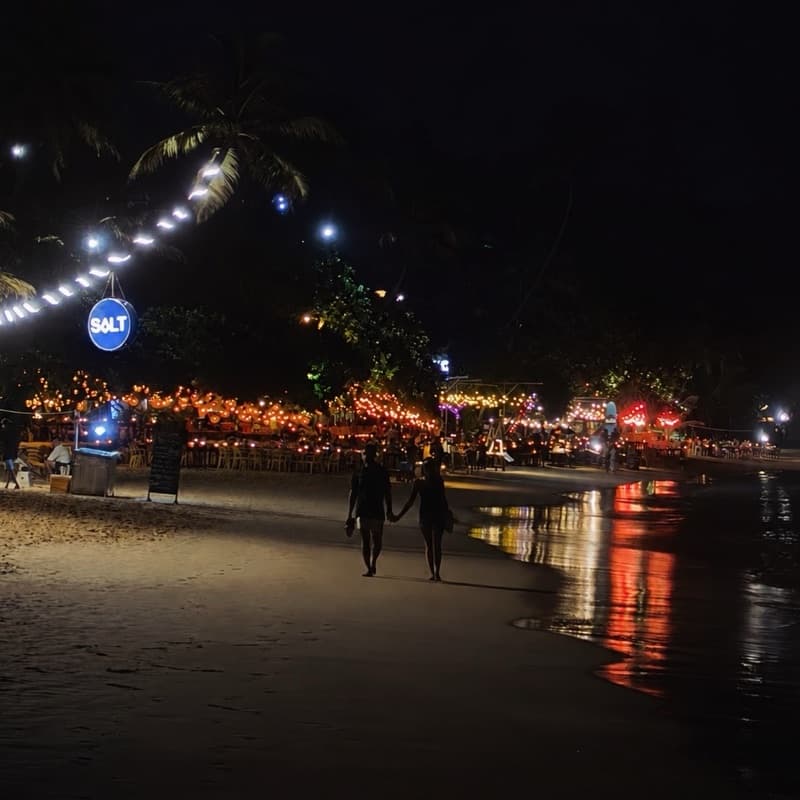 A lakeside promenade strung with lights after dark