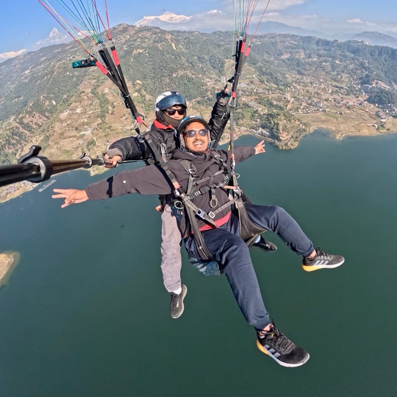 Tandem paragliding above a mountain lake